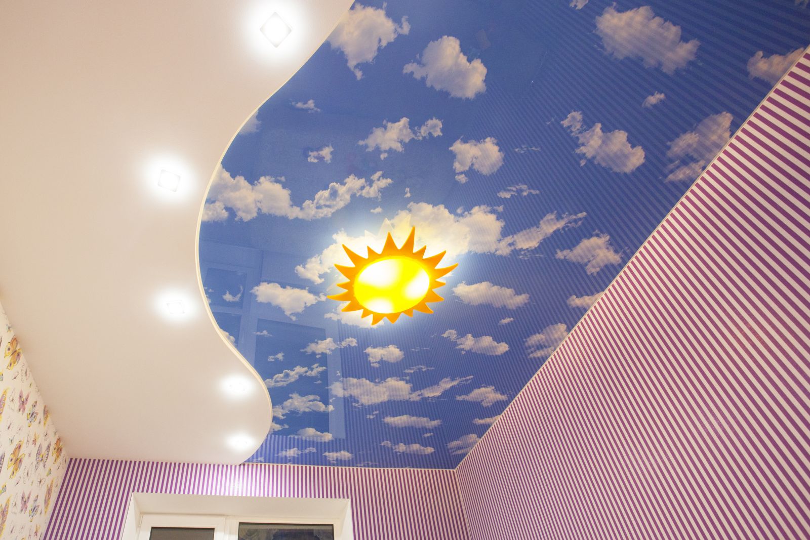 Двухуровневый потолок без подсветки, на нижнем уровне потолка расположены встраиваемые светильники вдоль линии перехода, на верхний уровень нанесена фотопечать "небо с облаками"